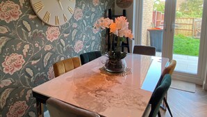 A dining area with a large floral wallpaper, a marble table, and two pendant lights. - Cozy Bedford Home with 3 Bedrooms (Bedford)
