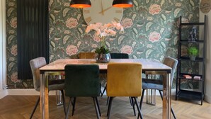 A dining area with a floral wallpaper, a round table, and chairs. - Cozy Bedford Home with 3 Bedrooms (Bedford)