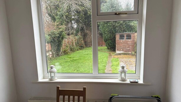 Une pièce comprenant une table à manger, deux chaises, un radiateur et une fenêtre ornée de deux lanternes blanches.