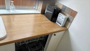 Une cuisine dotée d’un plan de travail en bois, d’un lave-vaisselle et d’une machine à café.