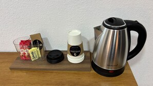 A coffee station with a coffee maker, a cup of coffee, and various coffee pods on a wooden table.
