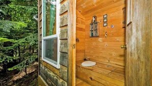 A wooden cabin with a window, a door, and a small sink.
