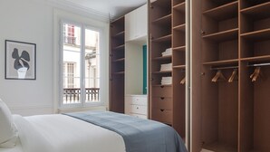 A bedroom with a bed, a large wardrobe, and a window with a view of a balcony. - Blueground | Épinettes, view, nr Parc Monceau (Paris)