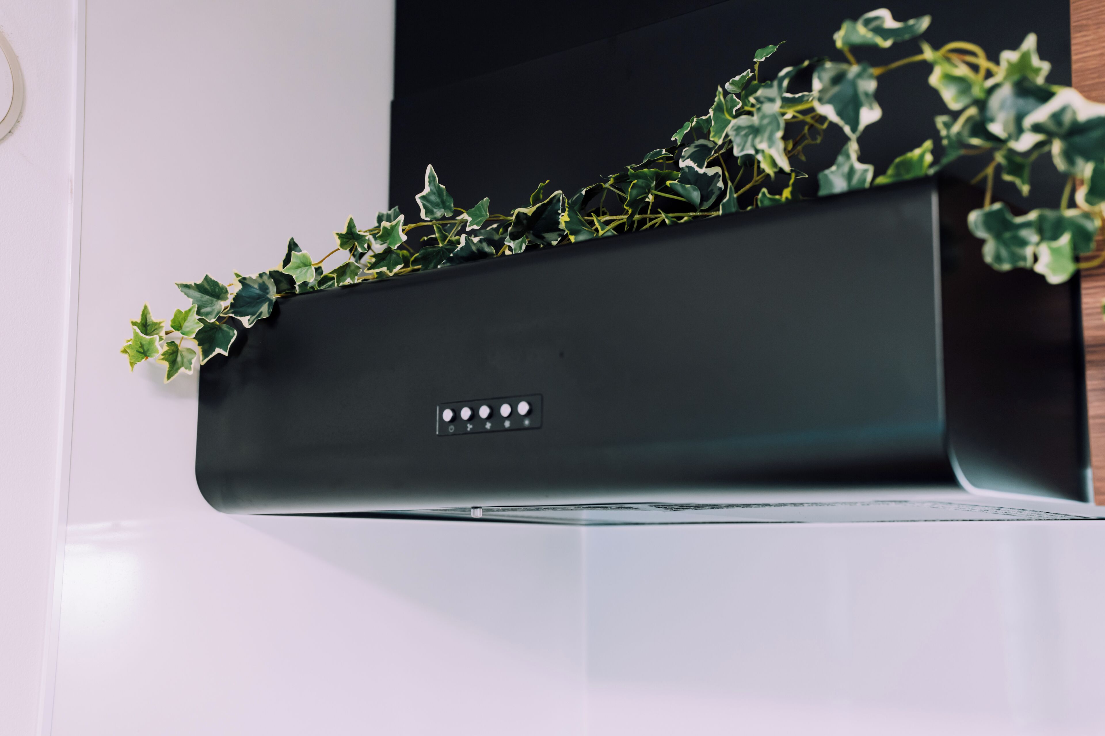 Un dispositivo negro y rectangular fijado a la pared, con un panel de control que incluye cuatro botones y una pantalla pequeña.
