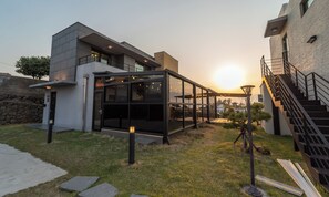 A modern building with a glass extension, a staircase, and a stone wall in the background.