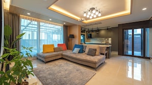 A modern living room with a sectional sofa, a dining area, and a kitchen. - Jeju Calma (Jeju City)