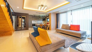 A modern living room with a sofa, a dining area, and a kitchen. - Jeju Calma (Jeju City)