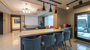A modern kitchen with a central island, bar stools, pendant lighting, and a view of the outdoors. - Jeju Calma (Jeju City)