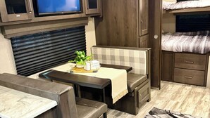 Compact RV interieur met kitchenette, zithoek en een televisie waarop 'NETFLIX' wordt afgespeeld.