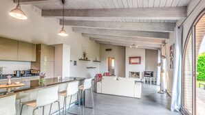 A modern kitchen with a bar area, a living room with a sofa and chairs, and a dining area with a table and chairs. - Luxurious home in Trequanda with house a panoramic view (Trequanda)
