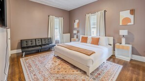 Une chambre avec un grand lit, un canapé, une table de chevet et un téléviseur.