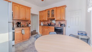 Une cuisine avec des meubles en bois, une table à manger et un ventilateur de plafond.