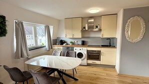 Una cocina moderna con comedor, que incluye una mesa y sillas, lavadora y un espejo grande en la pared.