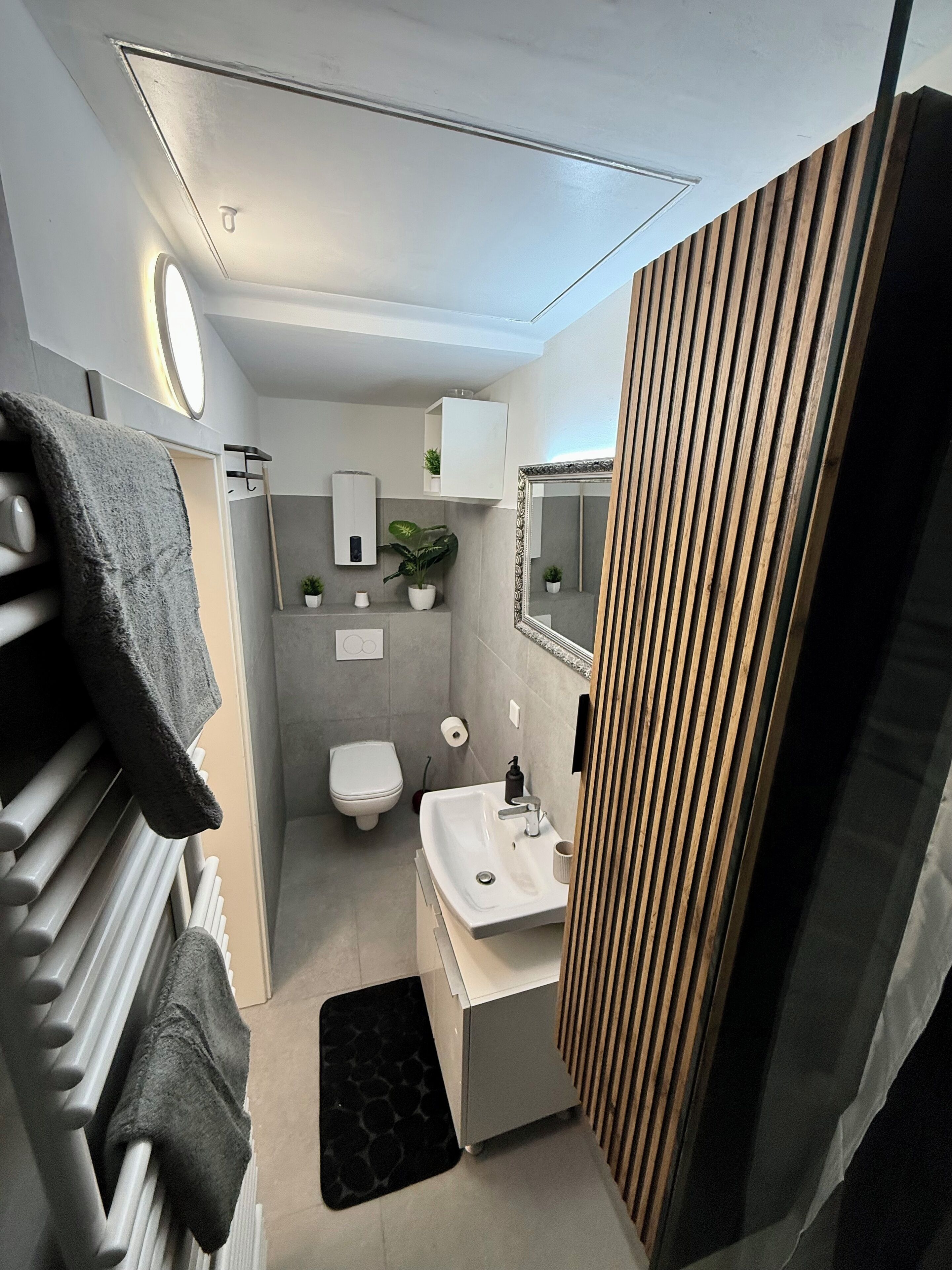 A compact bathroom with a toilet, sink, and towel rack.