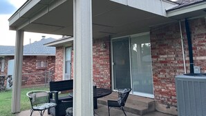 A covered patio with a brick wall, a sliding glass door, and outdoor furniture. - Aimee's Place- Comfy and  Close to Everything! (Moore)