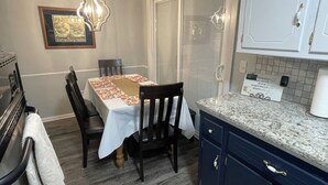 A dining area with a table set for two, a chandelier, and a kitchen with cabinets and a countertop. - Aimee's Place- Comfy and  Close to Everything! (Moore)