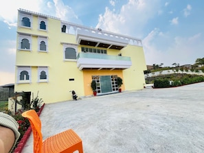 A two-story building with a yellow facade, a balcony, and a gated entrance.