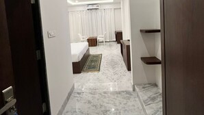 Een hotelkamer met een bed, een bureau, een stoel, een kledingkast en een badkamer met douche en toilet.