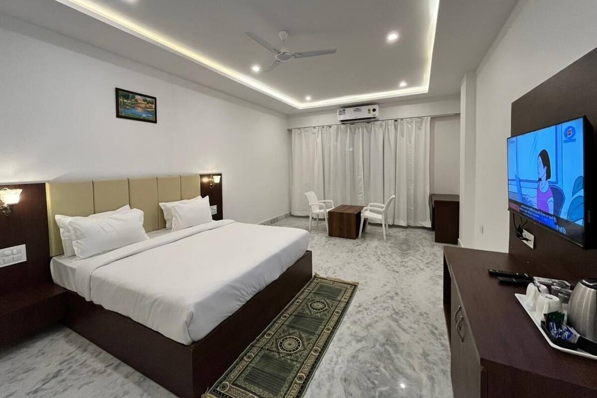 Une chambre d’hôtel moderne équipée d’un grand lit, d’un bureau, d’une télévision et d’un ventilateur de plafond.