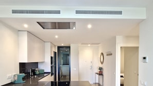 A modern kitchen with a central island, built-in appliances, and a hallway leading to a bedroom. - SR Calanova Golf 2BDR with private garden (Mijas)