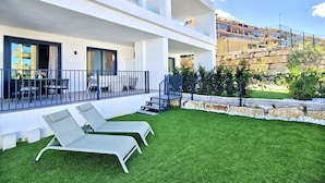 A modern hotel with a flat roof, a balcony with outdoor seating, and a well-maintained lawn. - SR Calanova Golf 2BDR with private garden (Mijas)