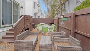 Un patio con mobiliario de mimbre, una valla de madera y una señal de calle que dice "MARGARITAVILLE".