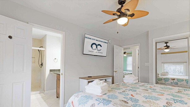 Un dormitorio con cama, ventilador de techo, ducha y un cartel de Ocean City Vacation Homes.