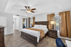 A bedroom with a large bed, a nightstand, a desk, a chair, and a ceiling fan. - Fin & Tonic~Heated Pool~Sleeps 12~Elegant Cape Coral Retreat (Cape Coral)