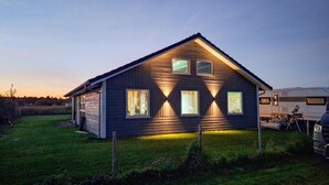 Een houten huis met twee verdiepingen, een puntige dakkapel, meerdere ramen en een veranda.