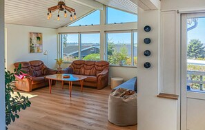 Een ruime woonkamer met leren banken, een houten salontafel en grote ramen met uitzicht op het omliggende landschap.