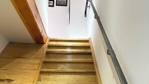 A wooden staircase with a metal handrail, white walls, and framed pictures on the wall. - Mas St-Jean: Charm, Climate & Garden in Provence (saint pierre de mezoargue)