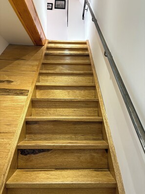 Eine Holztreppe mit Metallgeländer, weißen Wänden und gerahmten Bildern an der Wand.