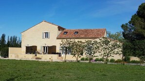 A two-story house with a tiled roof, a front porch, and a small garden area. - Mas St-Jean: Charm, Climate & Garden in Provence (saint pierre de mezoargue)
