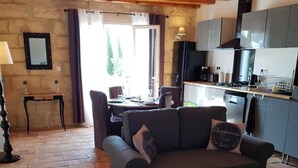 A cozy living room with a sofa, a coffee table, and a dining area with a table and chairs. - Mas St-Jean: Charm, Climate & Garden in Provence (saint pierre de mezoargue)