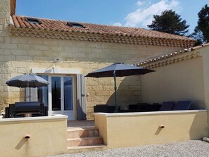 Un patio con posti a sedere all'aperto, un barbecue e un ingresso coperto.