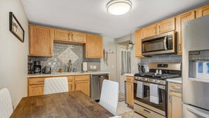 A kitchen with wooden cabinets, a stainless steel refrigerator, a microwave, and an oven. - 1014a Swope (Colorado Springs)