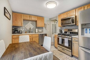 Eine Küche mit Holzausstattung, einem Edelstahlkühlschrank, einer Mikrowelle und einem Backofen.