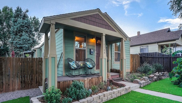 A small house with a porch, two rocking chairs, and a stone retaining wall. - 1014a Swope (Colorado Springs)