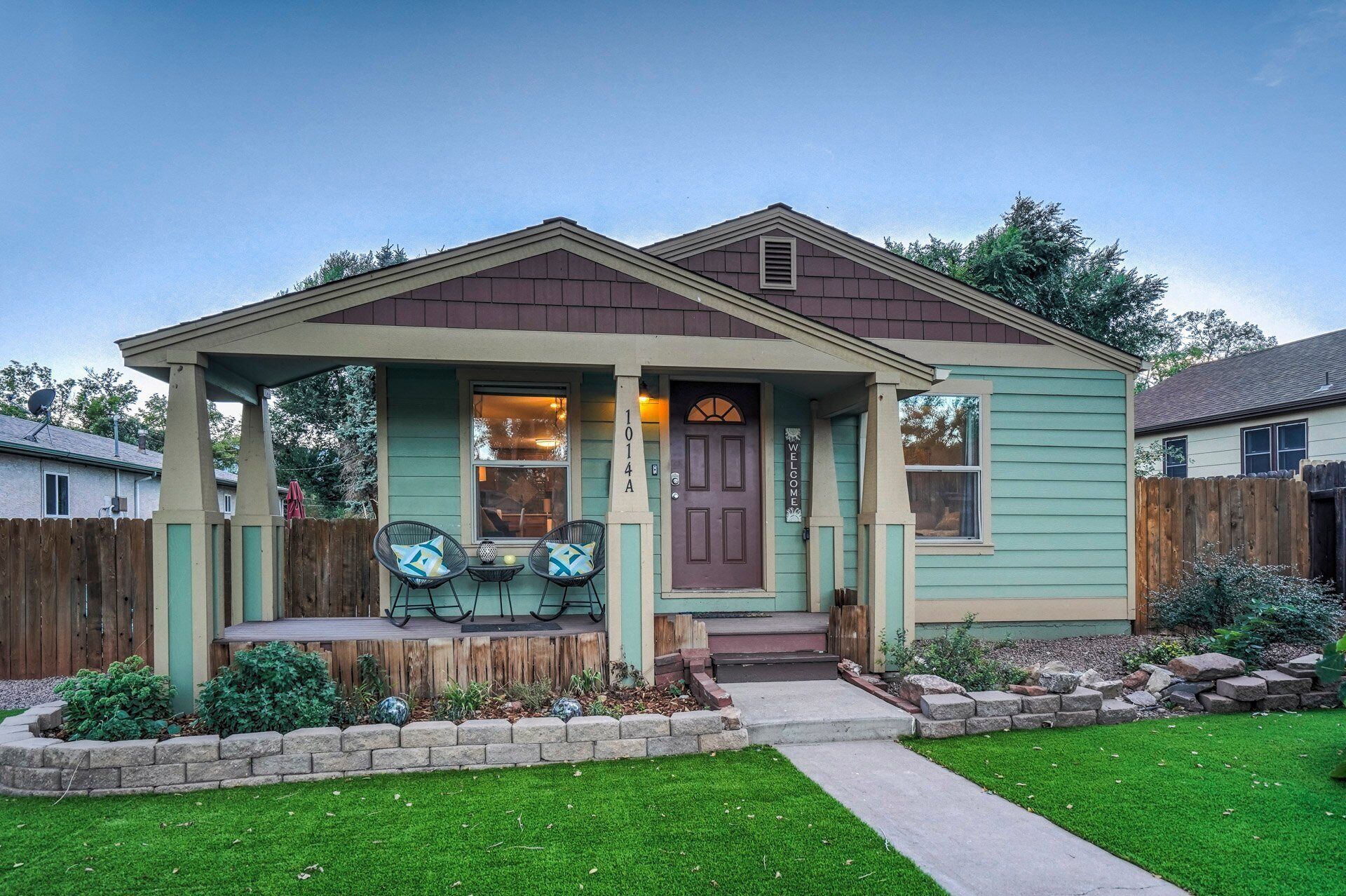 A small, single-story house with a front porch, a mailbox, and a welcome sign.