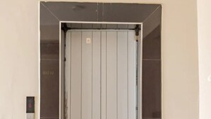 En elevator med lukket dør, et kontrolpanel på væggen og et flisebelagt gulv.