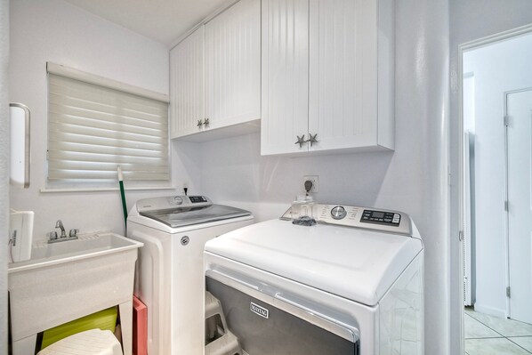 Una sala de lavandería con lavadora, secadora y pileta.