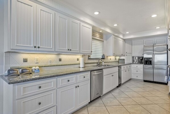 A kitchen with white cabinetry, a stainless steel refrigerator, a dishwasher, and a granite countertop. - 1409 S Pacific Street (Oceanside)