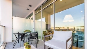 Een balkon met een eettafel, stoelen, een witte bank en potplanten.
