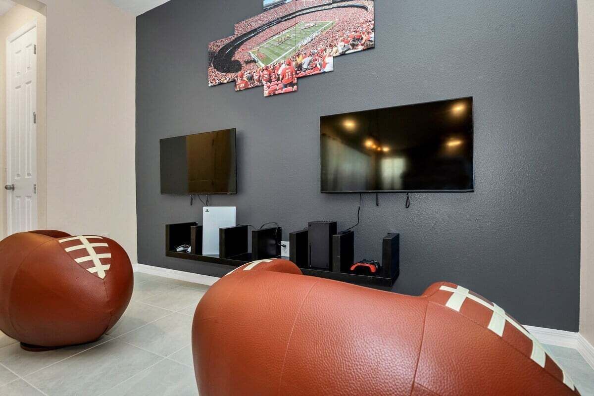 A living room with two large leather sofas, a mounted TV, and a shelf with speakers.