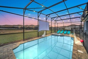Una piscina con cerramiento de vidrio, rodeada de sillas de descanso y vistas a edificios residenciales.