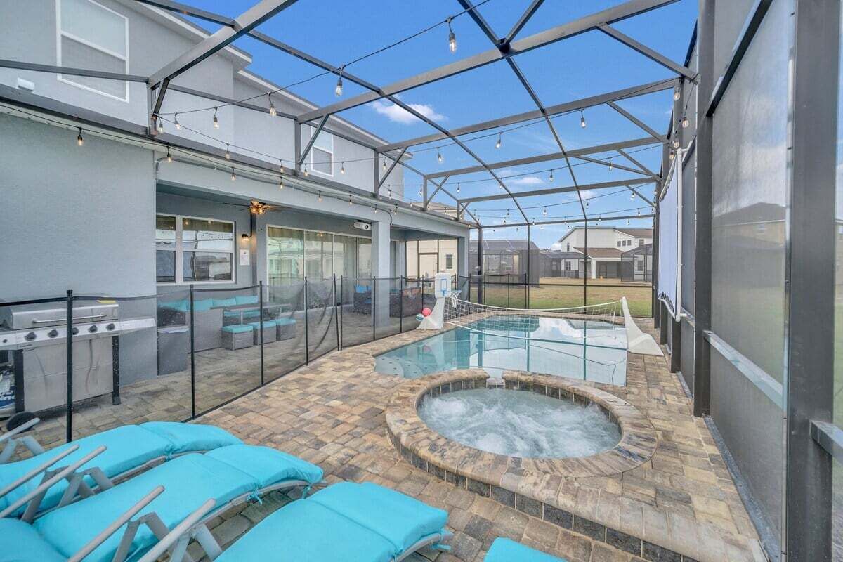 A covered outdoor area with a hot tub, lounge chairs, and a grill.