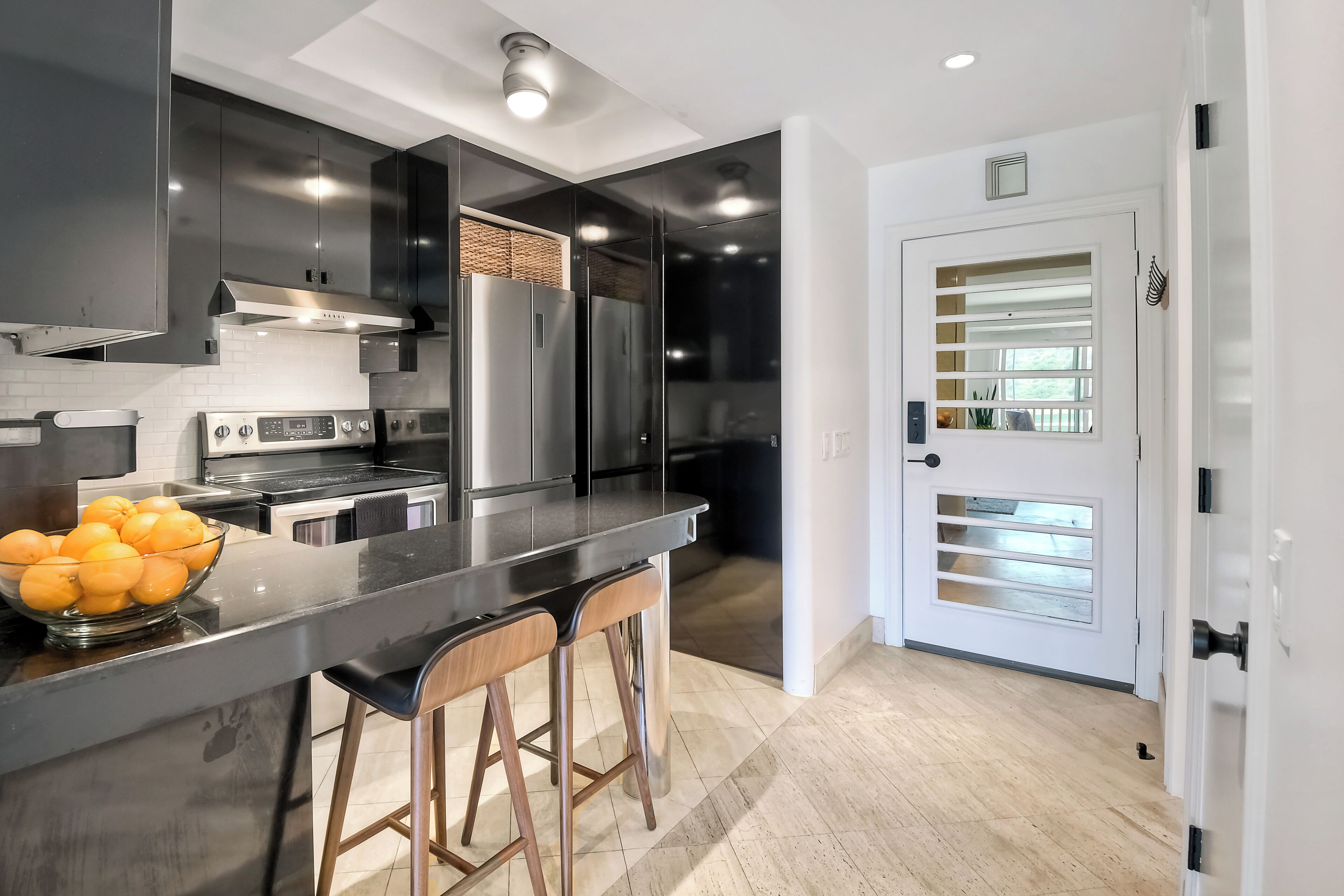 A modern kitchen with a large island, stainless steel appliances, and a white door with a window.