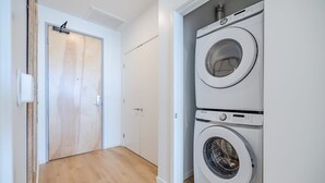 Ein Waschraum mit zwei übereinander gestapelten Frontlader-Waschmaschinen und einer Holztür.