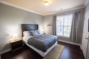 A bedroom with a large bed, two bedside tables, a nightstand, a window with curtains, and a door. - 1370 Tuscana LN Davenport, 3bed (Davenport)
