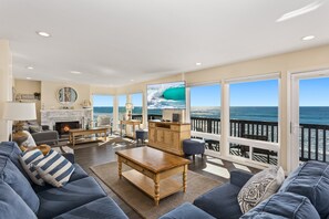 A spacious living room with a large window overlooking the ocean, a fireplace, and a comfortable seating area. - 1317 S Pacific - Entire Home (Oceanside)